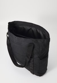 Borsa a tracolla nera realizzata in tessuto resistente, con un ampio interno, tracolla regolabile in tessuto intrecciato e tasche laterali per ulteriore spazio di almacenamiento.