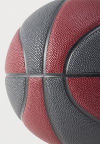 Minge de baschet din cauciuc cu suprafață texturată, cu secțiuni roșii și gri separate de cusături negre, evidențiind forma sa sferică.