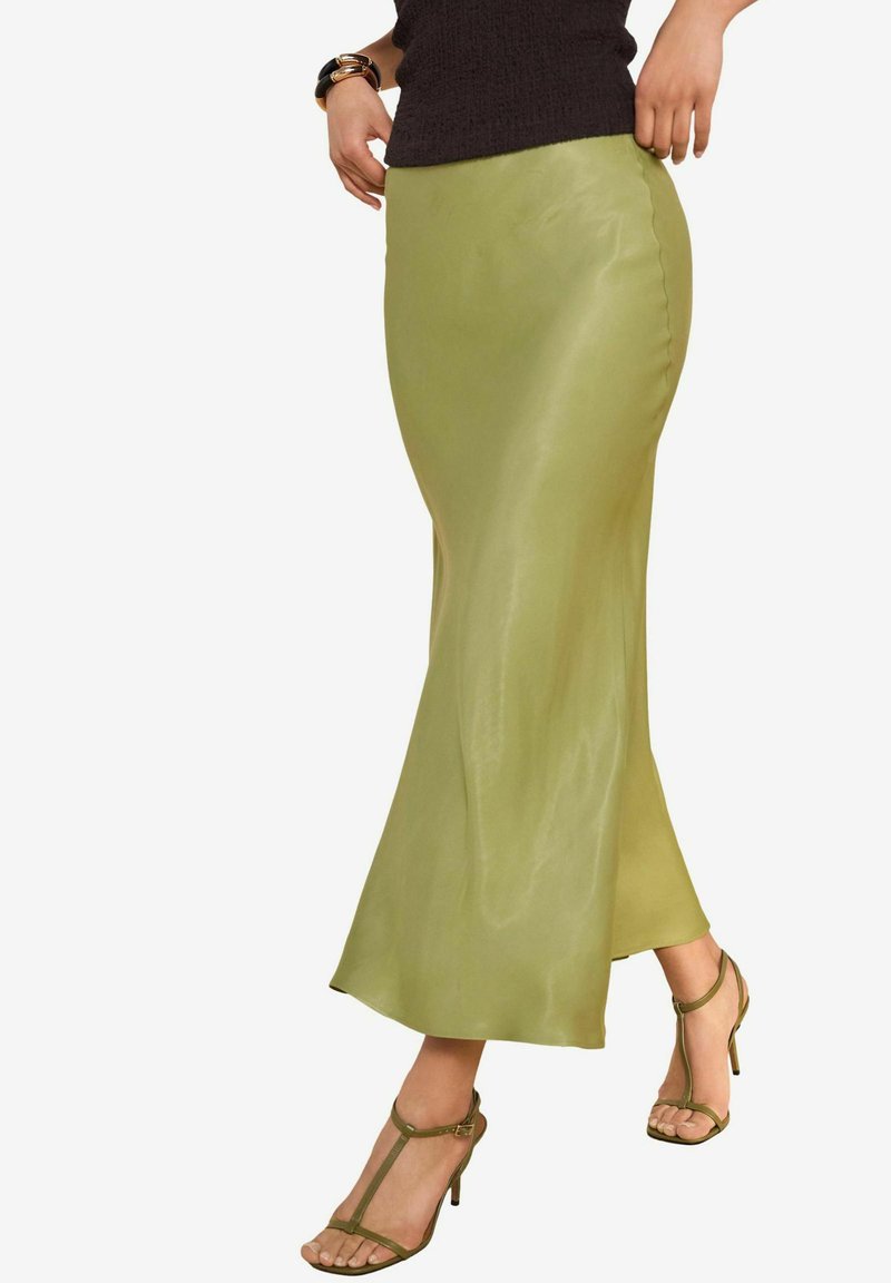 Green satin maxi skirt with a fitted waist and flared hem, paired with matching strappy sandals. The fabric has a smooth, glossy finish.