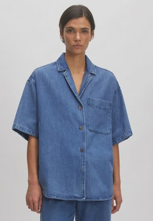 Blauwe denim korte mouwen shirt met een notch-kraag, borstzak en bruine knopen. Heeft een losse pasvorm en een textuurstof.