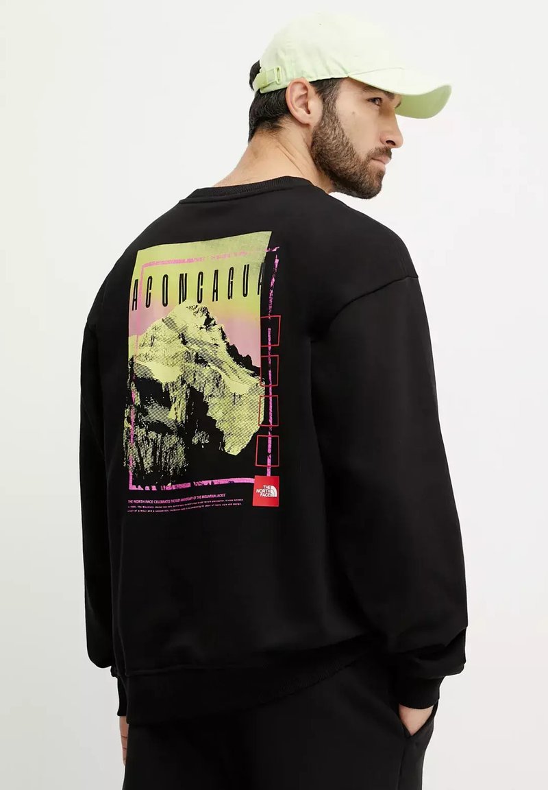 Sudadera negra con un estampado gráfico que presenta una montaña y colores vivos. Los detalles adicionales incluyen puños de canalé y un diseño de cuello redondo.