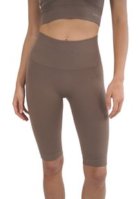 Pantaloni sportivi marroni a vita alta con una vestibilità aderente, realizzati in tessuto elastico. Presentano una texture a coste e un logo discreto sul lato.