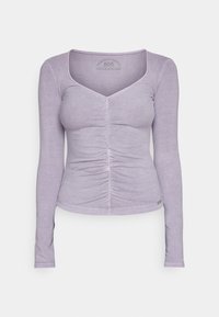 Langärmliges Oberteil in hellem Lavendel mit taillierter Silhouette, V-Ausschnitt und gerafften Details in der Mitte vorne. Weicher Baumwollmischstoff.