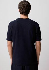 T-shirt bleu marine à manches courtes en tissu texturé, avec un col rond et des coutures plates sur les épaules et les manches.