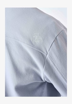 Lichtgrijs stoffen shirt met een geribbeld textuur; bevat een geborduurd logo op de schouder. De snit biedt een moderne pasvorm.