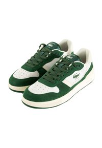 Sneaker in suede verde e pelle bianca con punta perforata, lacci abbinati e linguetta verde con marchio. Presenta una suola in gomma bianca testurizzata.