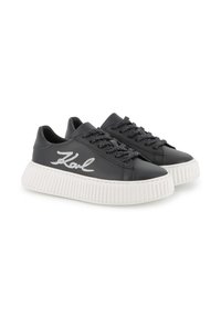 Black leather sneakers with a white ridged sole, featuring black sparkly laces and a white "Karl" logo embellished on the side.