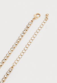 Χρυσό βραχιόλι με καθαρούς στρογγυλούς κρύσταλλους και ρυθμιζόμενο κλείσιμο με αλυσίδα σε λευκό φόντο.