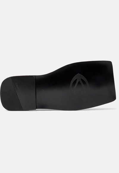 Sål af sort lædersko med firkantet tå, præget logo nær fronten og mærkenavn på hælområdet. Størrelse 42 markeret på sålen.