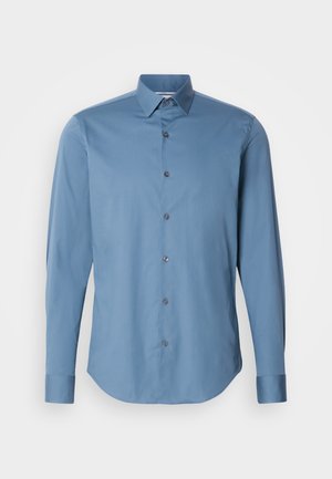 Hele sinine nupp-särk, mis on valmistatud siledast kangast, klassikalise krae, pikkade varrukate ja kuue kontrastse nupuga ümaras servas.