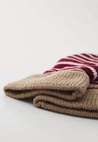 Moufles tricotées avec un poignet côtelé marron et un motif rouge présentant des rayures horizontales. Tissu doux et texturé avec des détails de couture visibles.