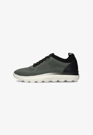 Zapatilla deportiva en textil verde oscuro con detalles en negro, suela ligera acolchada con patrón ondulado y cuello de punto para mayor comodidad.