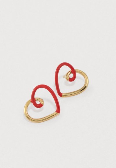 Raudonos širdies formos auskarai blizgiu paviršiumi su auksinės spalvos metalinėmis detalėmis; juose yra žaismingas suktuko dizainas.