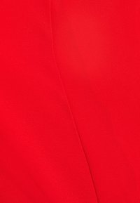 Tessuto rosso con una consistenza morbida e liscia, caratterizzato da una leggera lucentezza. La superficie è uniforme, senza motivi o decorazioni evidenti.