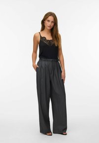 Zwarte cami-top met kantwerk, gecombineerd met hooggeknipte, wijde grijze broek. Glad materiaal met een geplooid ontwerp en zijzakken.