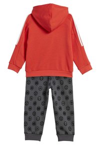 Felpa rossa con cappuccio e strisce bianche sulle maniche, abbinata a pantaloni del pigiama grigi con simboli di supereroi neri in un motivo ripetitivo.