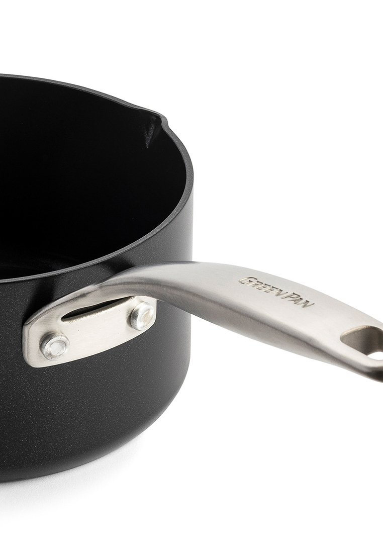 Czarny garnek o zaokrąglonym kształcie i stalowej rączce, z nitowanym wzorem i niewielkim dziobkiem.