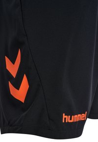 Zwarte sportshorts gemaakt van glad stof, met oranje chevronlogo's en "hummel" gedrukt op de zoom. Eenvoudig, functioneel ontwerp.