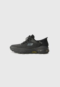 Zapatilla deportiva negra con parte superior de punto texturizado, logo en el lateral, cordones a tono y una suela acolchada con un acento de goma Goodyear.
