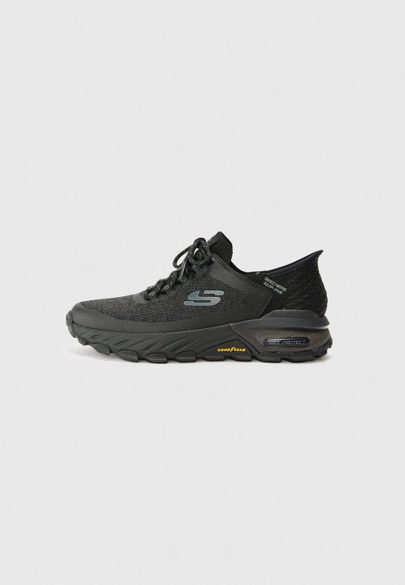 Zapatilla deportiva negra con parte superior de punto texturizado, logo en el lateral, cordones a tono y una suela acolchada con un acento de goma Goodyear.
