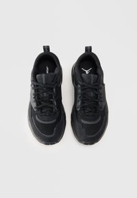 Par crnih atletskih tenisica sa mrežastim i antilop detaljima, crnim vezicama i brendiranim logotipima na jeziku i potplatu, prikazanih odozgo.