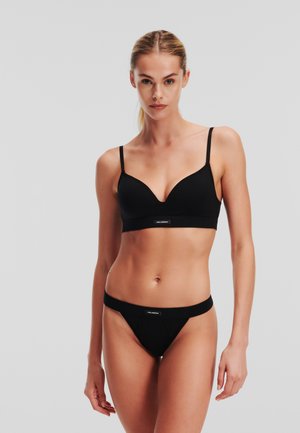 Zwarte katoenen bralette met verstelbare banden en een driehoekig cupdesign. Bijpassende zwarte katoenen string met een logo- tailleband, gladde textuur.