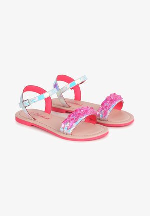 Sandales plates pour enfants avec des brides argentées irisées, une décoration chaîne rose sur le dessus des orteils, et des semelles roses, maintenues par des brides à boucle à la cheville.