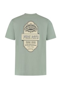 Lichtgroene katoenen T-shirt met een beige grafisch ontwerp op de achterkant, voorzien van decoratieve tekst en een badge-achtige vorm. Ronde hals en korte mouwen.