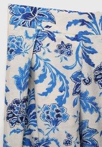 Blumige Stoffe mit blauen und marineblauen Mustern auf einem beigen Hintergrund, mit Blättern und Blumen in einer Mischung aus einfarbigen und gepunkteten Designs.