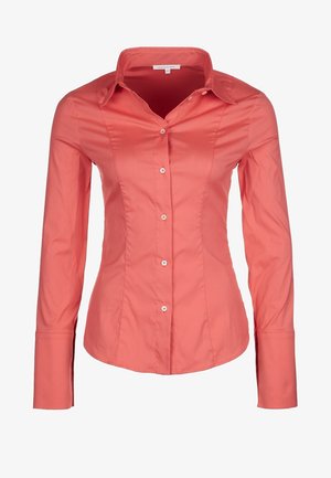 Lys koralfarvet, tætsiddende langærmet skjorte med spidse kraver og frontknaplukning. Lavet af glat stof med en let glans.