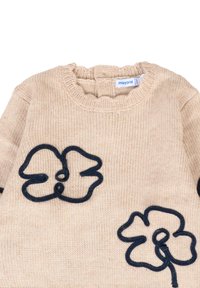 Beżowy sweter dzianinowy z prążkowanym dekoltem; na froncie znajdują się dwa granatowe aplikacje kwiatowe o teksturowym wykończeniu. Widoczna metka marki.