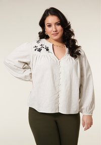 Witte blouse met zwarte strepen, voorzien van bloemdecoraties op de schouders, knoopsluiting aan de voorkant en lang, geplooid mouw.