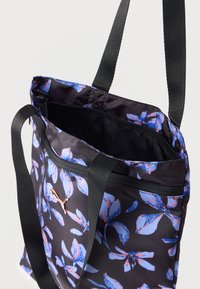 Μαύρη τσάντα ώμου με μπλε και ροζ φλοράλ μοτίβο, μαύρα λουριά, κλείσιμο με φερμουάρ και μικρό λογότυπο στο μπροστινό μέρος.