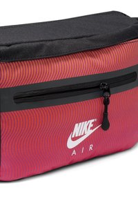 Nike Air -reppu, jossa on aaltoileva punainen ja violetti kuvio, musta yläosa, etutasku vetoketjulla ja valkoinen logo sivussa. Sujuva pinta.