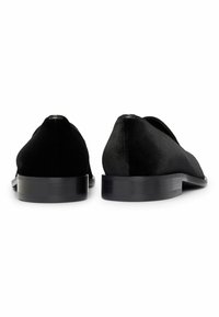 Scarpe in velluto nero con un design elegante, suole piatte e una texture liscia, caratterizzate da un leggero lucido e una forma della punta arrotondata.