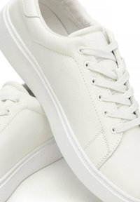 Sneakers bianchi in pelle con tomaia texturizzata, punta rotonda, lacci piatti e suola in gomma bianca dal design pulito.
