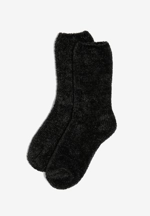 Chaussettes noires et duveteuses avec une texture douce. Design simple, longueur mi-mollet et orteils arrondis. Adaptées pour une utilisation par temps froid.