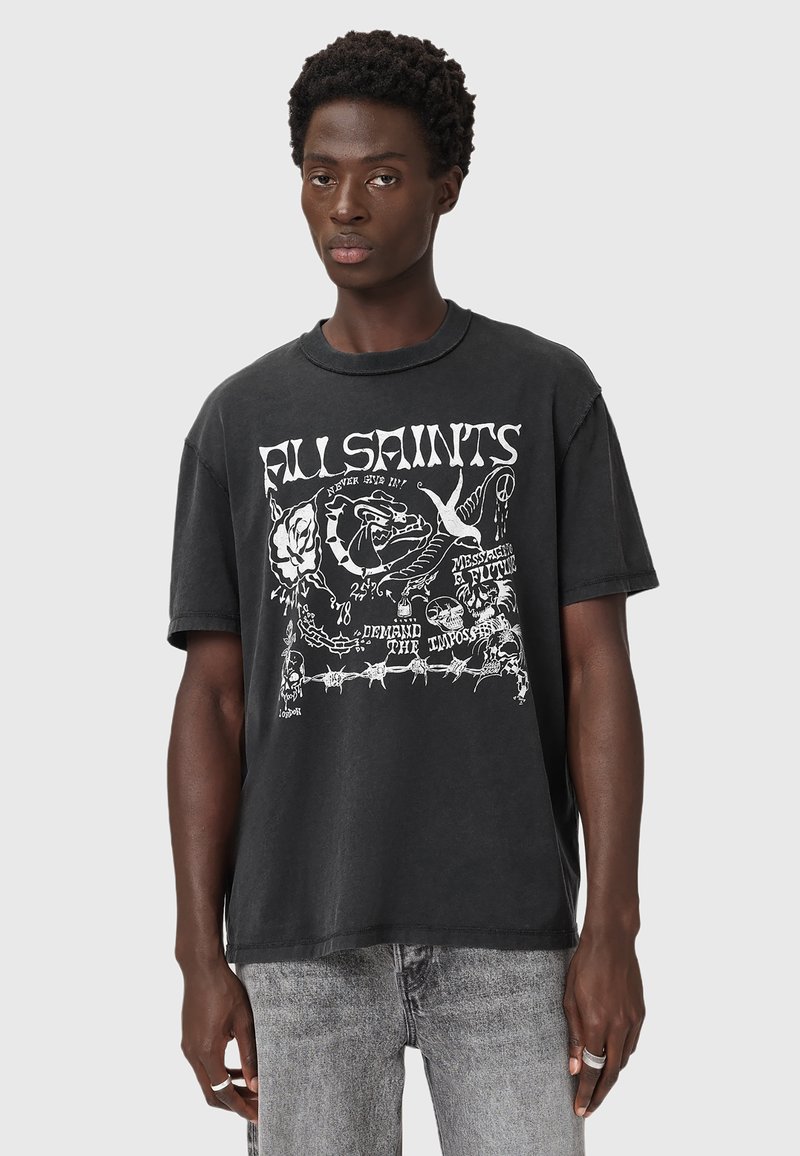 Camiseta negra de gran tamaño con estampado gráfico que presenta varios diseños en blanco, mangas cortas, cuello acanalado y textura de algodón suave.