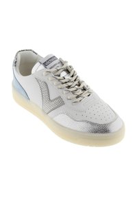 Zapatilla blanca y plateada de corte bajo con talón azul de ante, puntera perforada, cordones con diseño y suela translúcida.