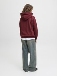 Burgunderfarget hettegenser med stor hette, løs passform, parret med vide lys blå denimjeans. Glatt tekstur, minimale dekorasjoner.