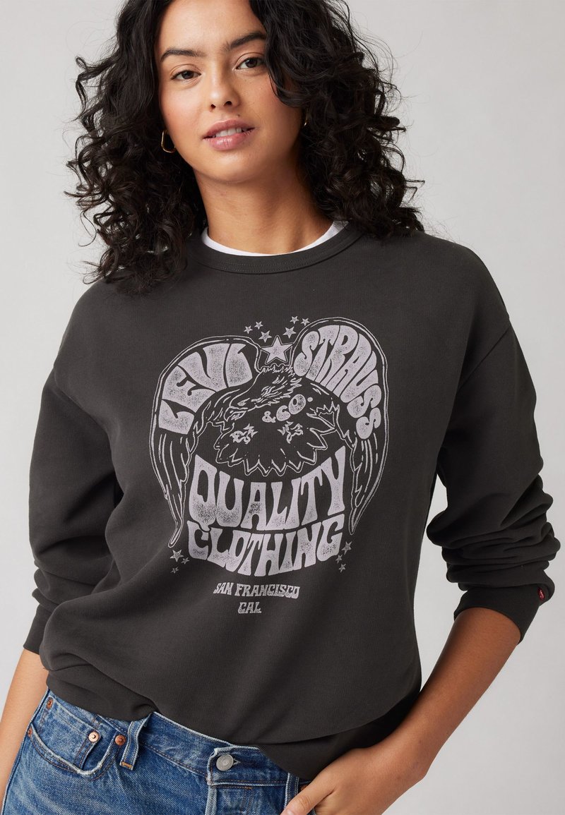 Sötétszürke pulóver, nagy fehér grafikai dizájnnal, amelyen a "Levi Strauss Quality Clothing" felirat és egy díszítő kép található. Klasszikus kerek nyakú stílus.