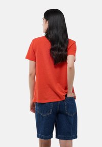 T-shirt rouge à manches courtes en coton doux, associé à un short en denim avec des revers et des poches arrière.