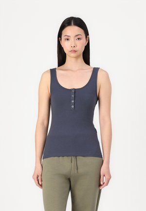 Donkerblauwe geribde tanktop met een ronde halslijn, voorzien van een knoopjeslijst en een slim fit, gecombineerd met olijfgroene trainingsbroek.