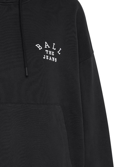 Černá mikina z kombinace bavlny s přední kapsou a kapucí se stahovací šňůrkou. Na hrudi vyšitý nápis "BALL THE JEANS" bílou barvou.
