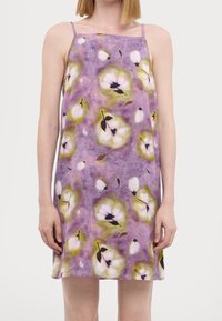 Robe fleurie en tissu violet avec un design aquarelle et des accents blancs et verts. Bretelles spaghetti, coupe décontractée, longueur genou.
