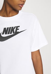 Maglietta in cotone bianco con un grande logo Nike nero sul petto, maniche corte e un design dal taglio rilassato.