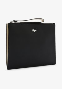 Borsa per documenti in tessuto nero con texture e logo Lacoste in argento, dotata di zip superiore e di un cinturino per polso staccabile. Interno beige.