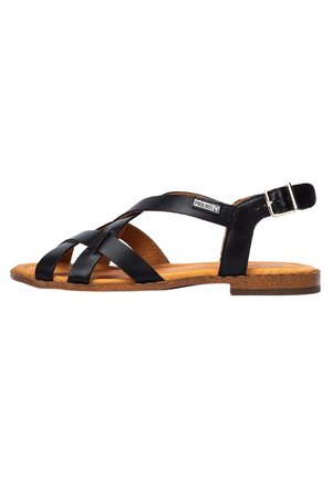 Czarne skórzane sandały z krzyżującymi się paskami, otwartymi bokami, regulowanym zapięciem kostki oraz brązową, teksturowaną wkładką na płaskiej korkowej podeszwie.