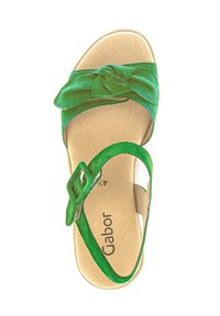 Groene sandal met een knoopdetail op de strap, gemaakt van zacht materiaal, met een enkelbandje met een vierkante gesp en een gestructureerde binnenzool.