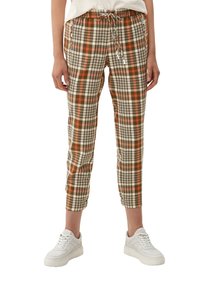 Pantalons cropped à carreaux en beige, orange et vert avec une taille élastique et un cordon de serrage ; associés à des baskets blanches.